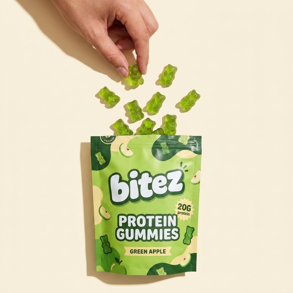 green apple bitez pouch with translucent green gummy bears spilled out and a hand picking one up